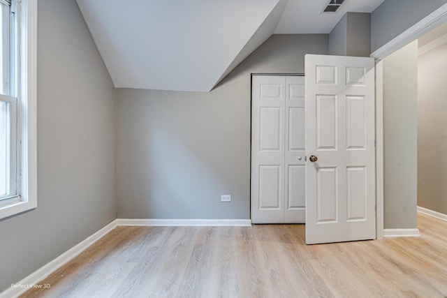 unfurnished bedroom featuring vaulted ceiling, light hardwood / wood-style floors, and a closet