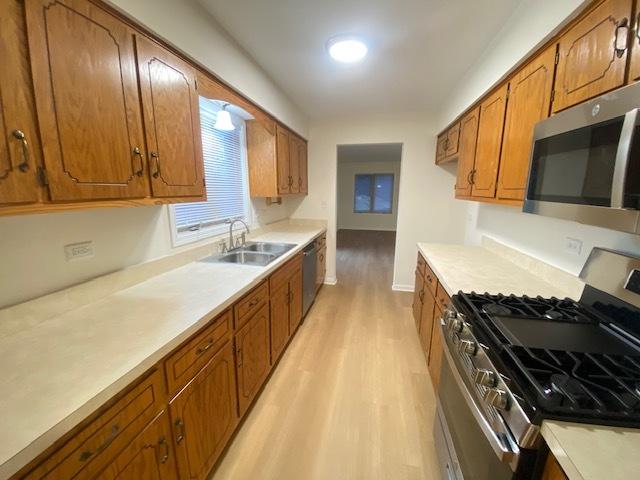 kitchen with sink, stainless steel appliances, and light hardwood / wood-style floors