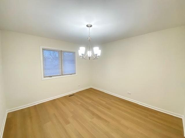 empty room featuring hardwood / wood-style floors and a notable chandelier