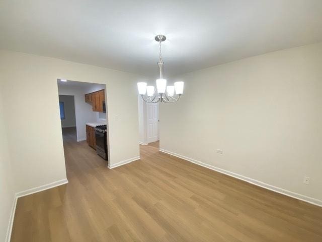 unfurnished dining area featuring a notable chandelier and light wood-type flooring