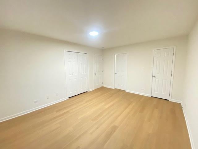 unfurnished bedroom with multiple closets and light hardwood / wood-style flooring