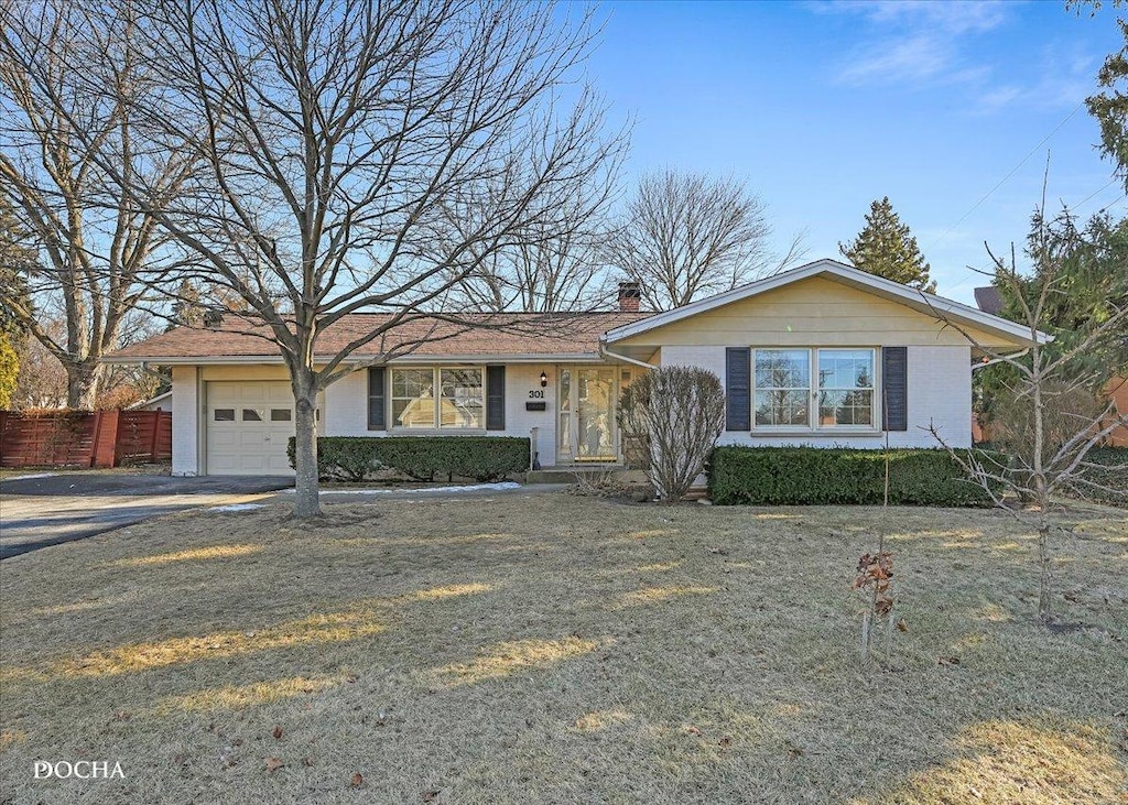 ranch-style home featuring a garage and a front lawn