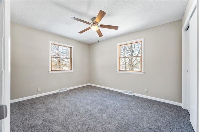 carpeted spare room featuring ceiling fan and a textured ceiling