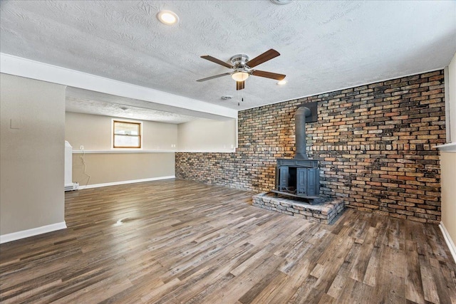 unfurnished living room featuring hardwood / wood-style flooring, ceiling fan, a textured ceiling, and a wood stove