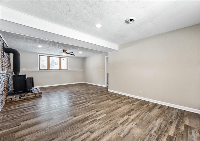 interior space with ceiling fan, hardwood / wood-style floors, a textured ceiling, and a wood stove