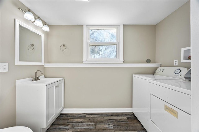 laundry area featuring sink, washing machine and dryer, and dark hardwood / wood-style floors