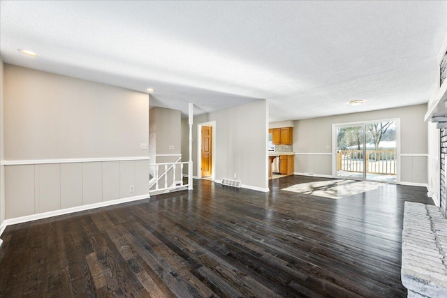 unfurnished living room featuring dark wood-type flooring and a textured ceiling