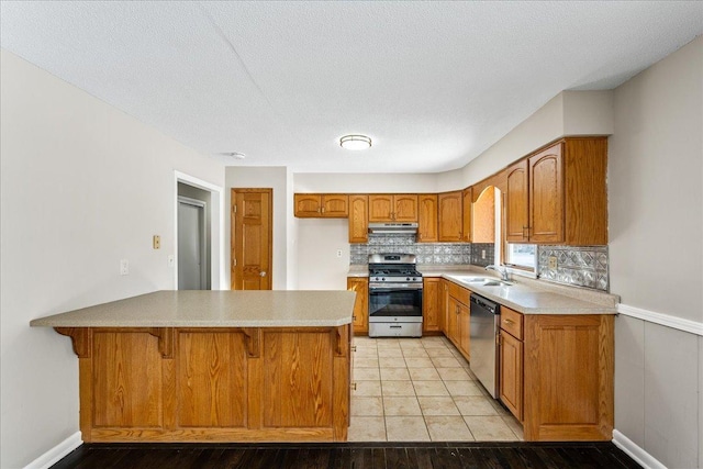 kitchen featuring a kitchen bar, sink, kitchen peninsula, stainless steel appliances, and decorative backsplash