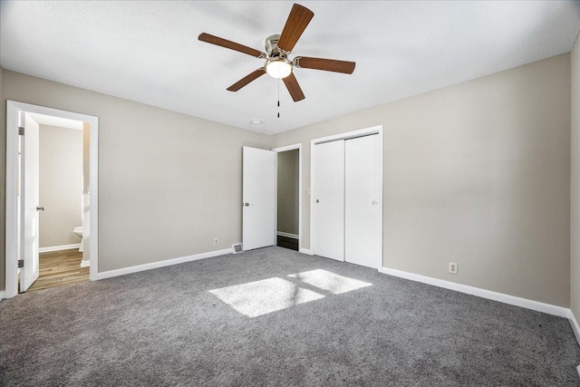 unfurnished bedroom with ceiling fan, dark carpet, a closet, and a textured ceiling