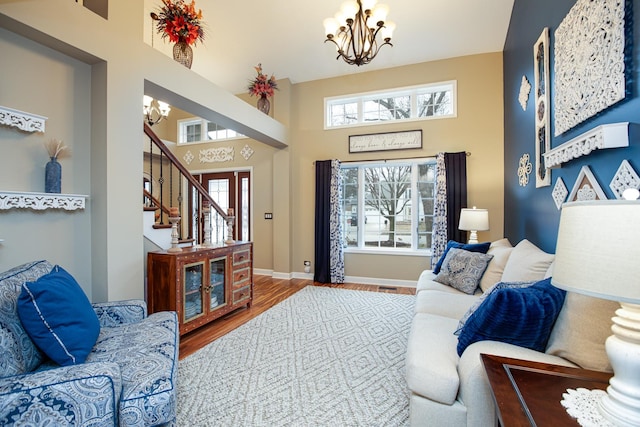 living room with an inviting chandelier, hardwood / wood-style flooring, and a towering ceiling