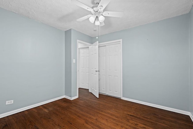 unfurnished bedroom with ceiling fan, a textured ceiling, dark hardwood / wood-style flooring, and a closet