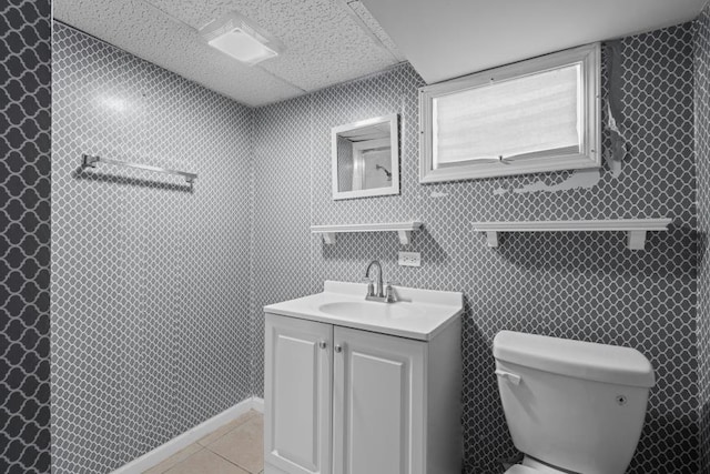 bathroom with a paneled ceiling, vanity, toilet, and tile patterned flooring