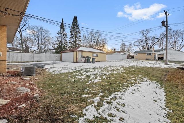 yard layered in snow featuring central AC unit, a garage, and an outdoor structure