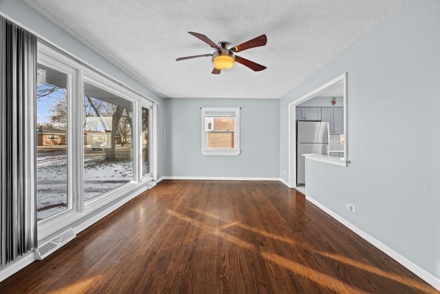 empty room with ceiling fan, dark wood-type flooring, and a textured ceiling