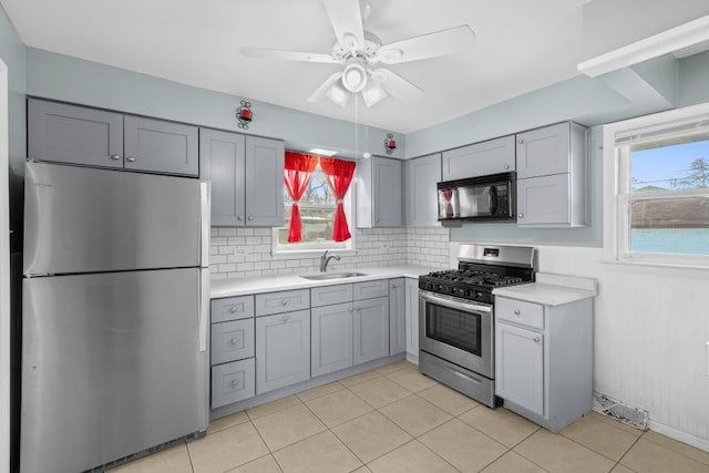 kitchen with sink, ceiling fan, appliances with stainless steel finishes, gray cabinetry, and decorative backsplash