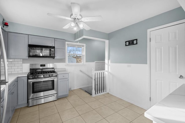 kitchen with gray cabinetry, stainless steel gas range oven, ceiling fan, and light tile patterned flooring