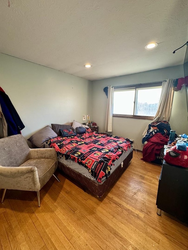 bedroom featuring light hardwood / wood-style floors and a textured ceiling