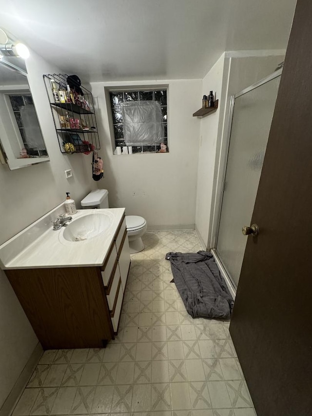 bathroom featuring vanity, a shower with shower door, and toilet