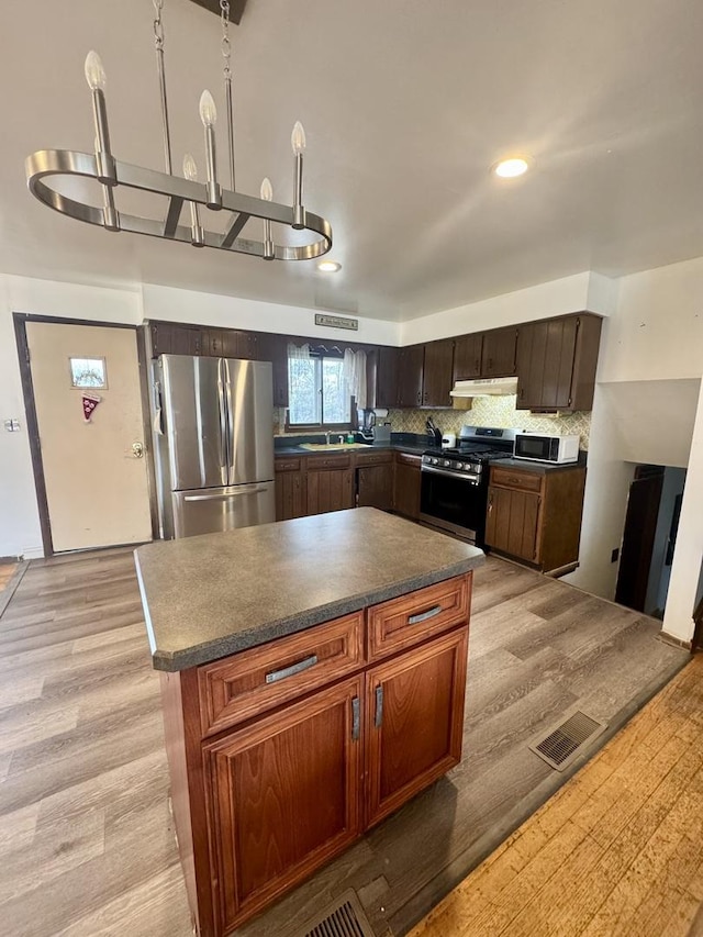 kitchen featuring decorative backsplash, light wood-type flooring, and appliances with stainless steel finishes