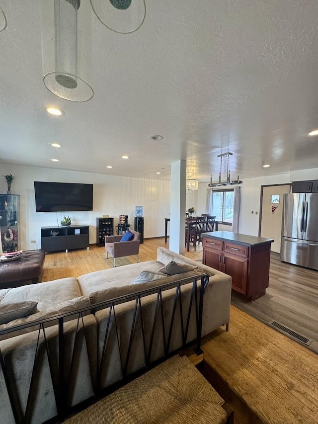 living room with a textured ceiling and light wood-type flooring