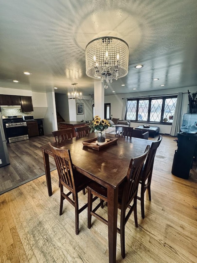 dining space with a textured ceiling, light hardwood / wood-style flooring, and a notable chandelier