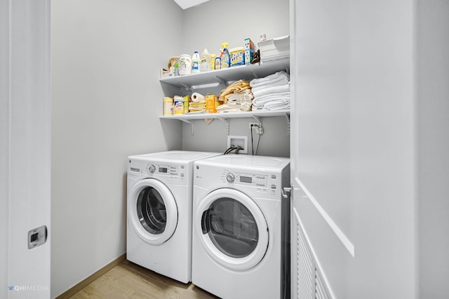 laundry room with separate washer and dryer and light hardwood / wood-style floors