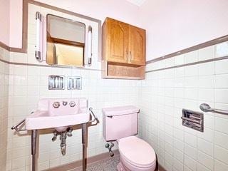 bathroom with tile walls and toilet