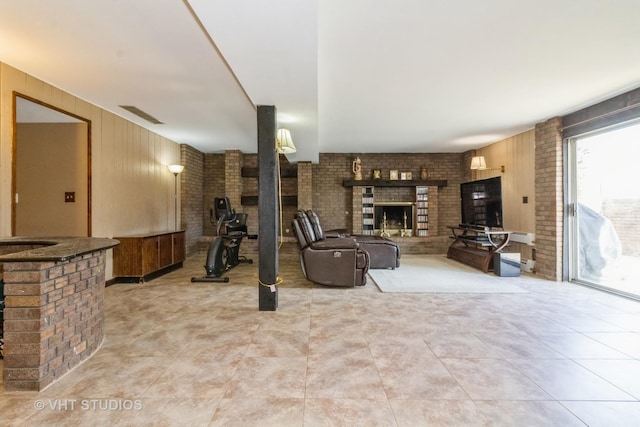 living room featuring brick wall, a brick fireplace, and wooden walls