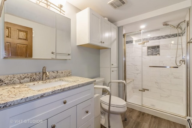 bathroom with hardwood / wood-style floors, vanity, baseboard heating, toilet, and a shower with door