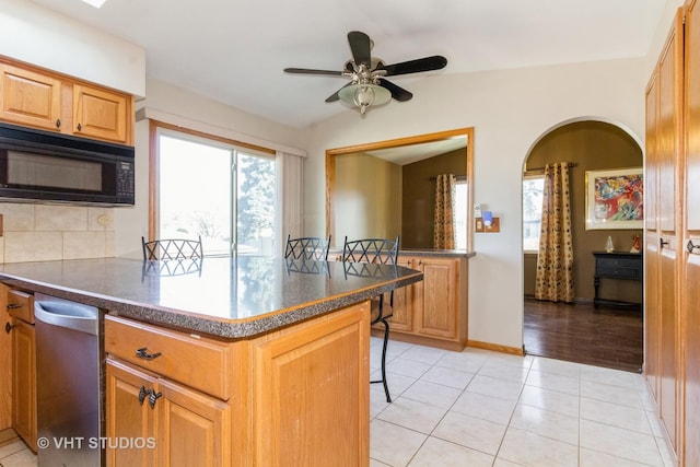 kitchen with light tile patterned floors, a breakfast bar area, vaulted ceiling, and plenty of natural light