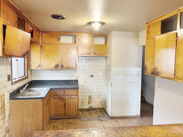 kitchen with sink, tile walls, and light wood-type flooring