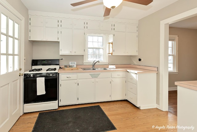 kitchen with sink, white cabinets, range with gas cooktop, and light hardwood / wood-style flooring