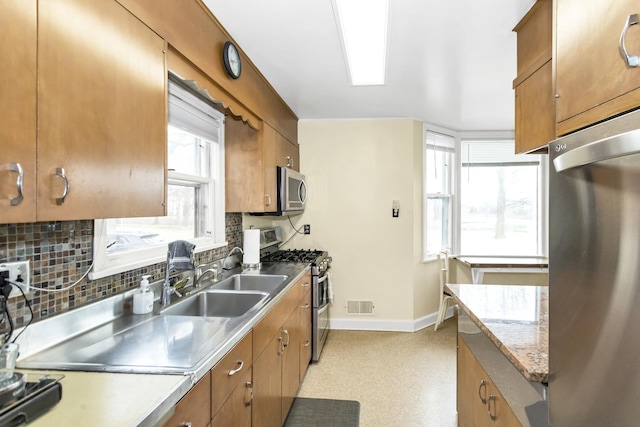 kitchen with tasteful backsplash, appliances with stainless steel finishes, and sink