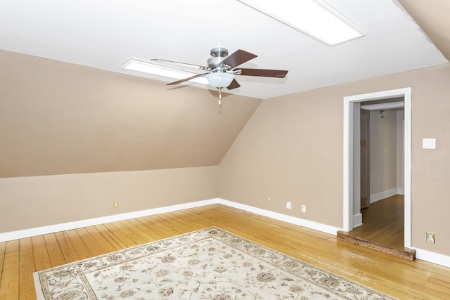 bonus room featuring ceiling fan, hardwood / wood-style flooring, and vaulted ceiling with skylight