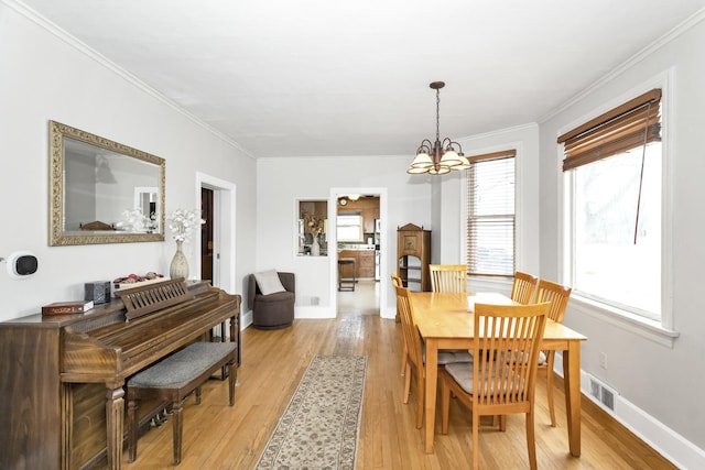 dining area featuring crown molding, light hardwood / wood-style floors, and a chandelier