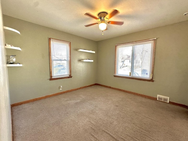 carpeted empty room featuring ceiling fan and a textured ceiling