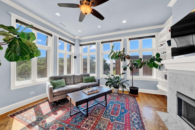 living room featuring hardwood / wood-style flooring, ornamental molding, and ceiling fan