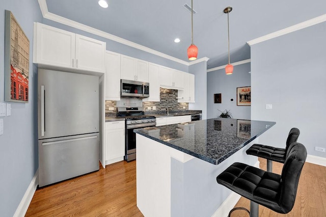 kitchen featuring pendant lighting, white cabinetry, stainless steel appliances, and light wood-type flooring