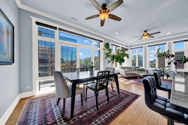 dining space with hardwood / wood-style floors, a wealth of natural light, and ornamental molding