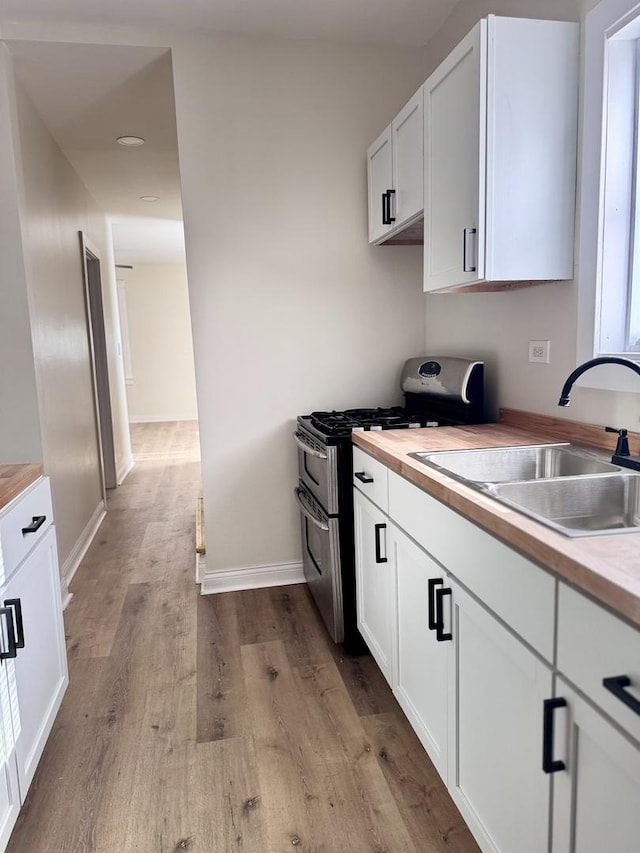 kitchen featuring white cabinetry, double oven range, sink, and butcher block countertops