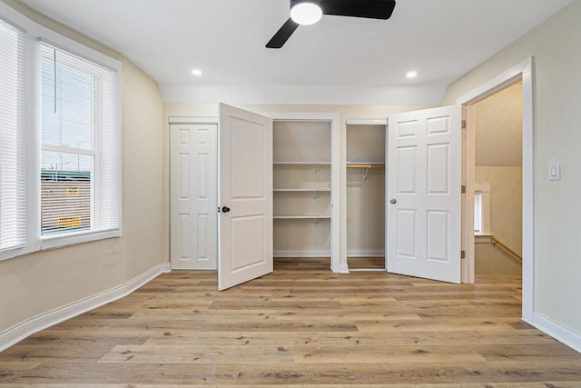 unfurnished bedroom featuring ceiling fan, two closets, and light hardwood / wood-style floors