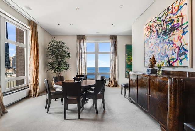 dining space with a water view and light carpet