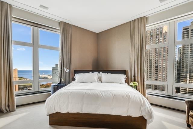 bedroom with a water view, light colored carpet, and a baseboard heating unit