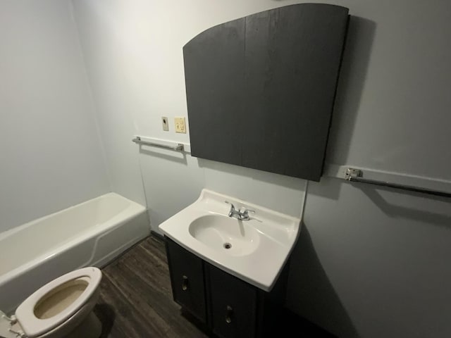 bathroom with vanity, hardwood / wood-style flooring, a tub, and toilet