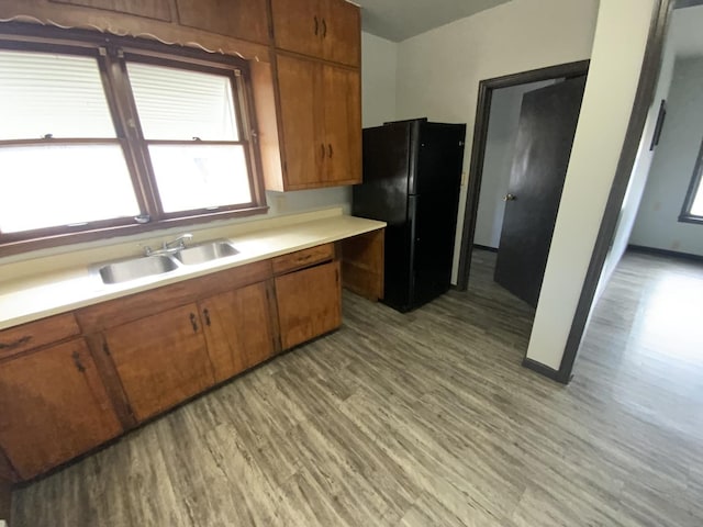 kitchen with sink, light hardwood / wood-style floors, and black fridge