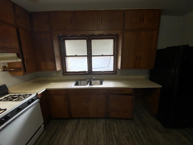 kitchen with black fridge, white range with gas cooktop, sink, and dark hardwood / wood-style floors