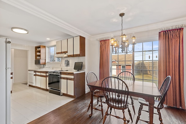 dining room with crown molding, sink, a chandelier, and light hardwood / wood-style floors