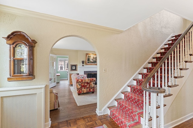 stairway featuring parquet floors and crown molding