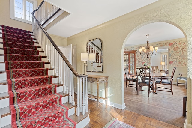 stairway featuring parquet floors, ornamental molding, and a chandelier