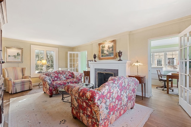 living room with french doors, ornamental molding, a fireplace, and light hardwood / wood-style floors